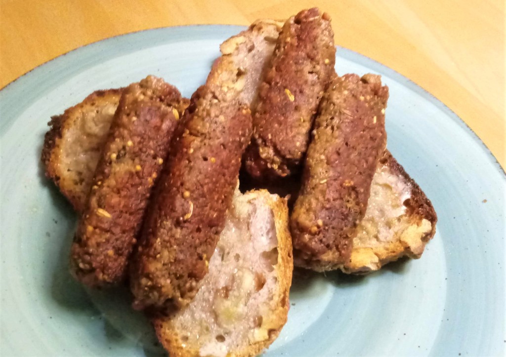 Four breakfast sausages on two slices of walnut bread are shown. The four sausages were made by combining one Impossible Burger with fennel and mustard seed, sage, thyme, and smoked paprika.