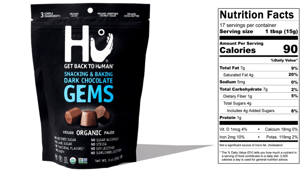 A bag of Hu Dark Chocolate Gems is pictured next to the Nutrition Facts panel for the product. a 15 g serving provides 90 calories, 7 g fat, 4 g saturated fat, 4 g sugars, and 1 g protein.