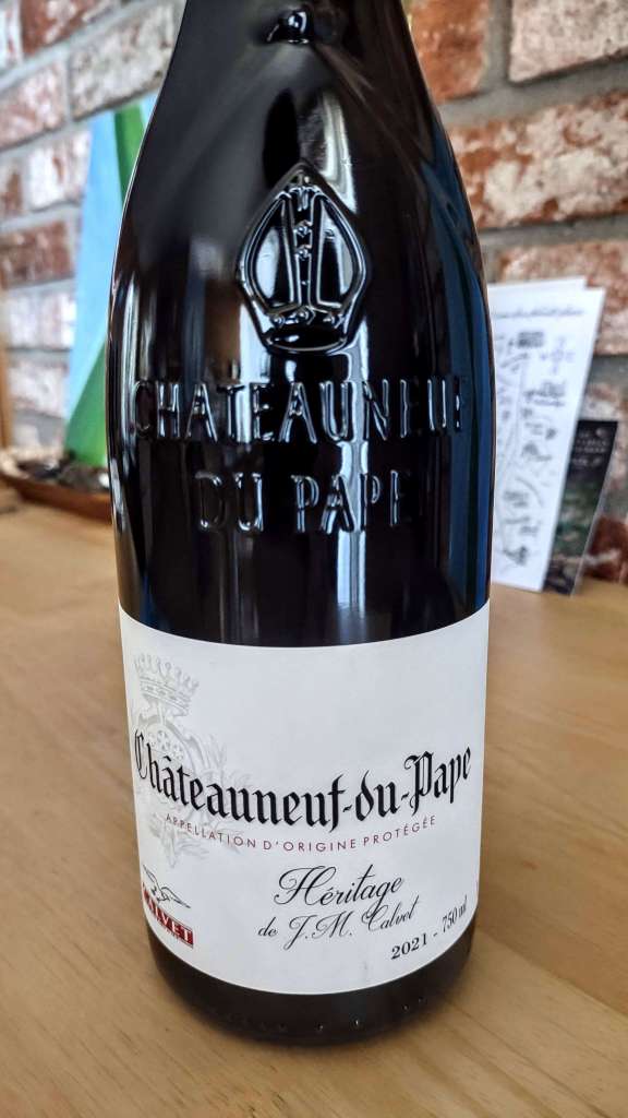 A photo showing a close up of a bottle of Calvet Châteauneuf-du-Pape with a red-brick wall in the background. 